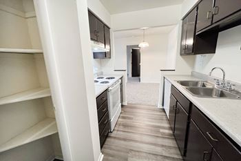 An empty kitchen with black cabinets and a white stove and sink